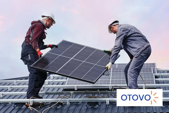 Zwei Personen installieren ein Solarmodul auf einem Dach.
