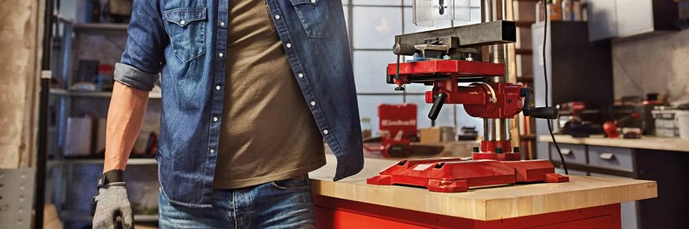 Person in Werkstatt mit Standbohrmaschine
