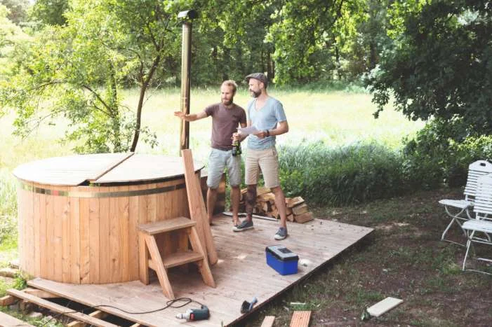 Zwei Personen bauen einen Whirlpool aus Holz