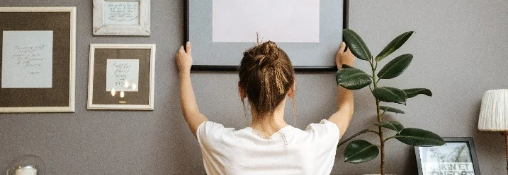 Person bringt Bilderrahmen an Wand an