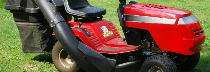 Roter Rasentraktor mit Grasfangkorb
