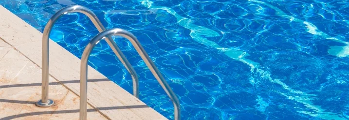 Leiter am Rand eines Pools mit blauem Wasser