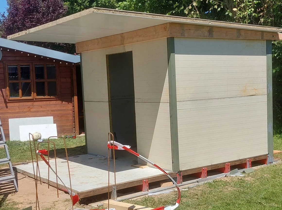 Eine Sauna im Rohbau auf einem Fundament im Garten.