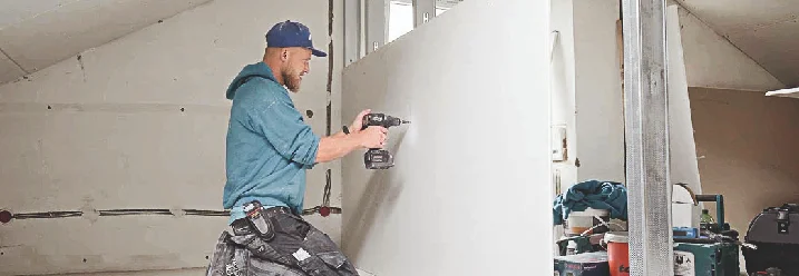 Person baut eine Wand in einem Dachstuhl ein.