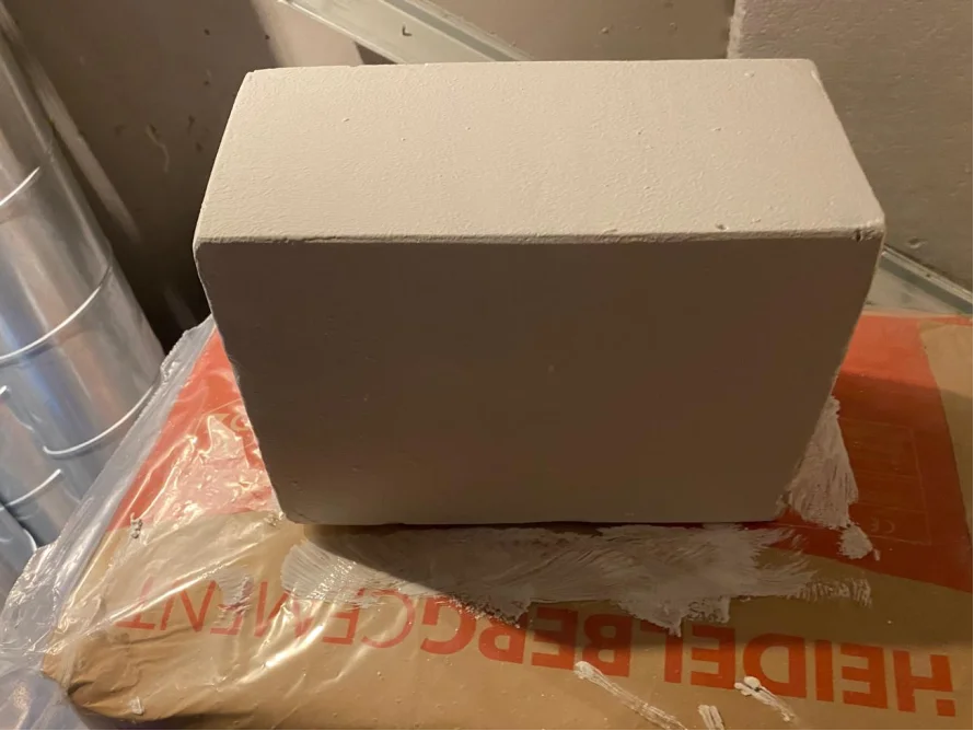 Weißer Betonstein auf einem Sack Zement