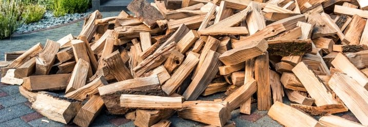 Ein großer Haufen Brennholz auf einer gepflasterten Einfahrt.