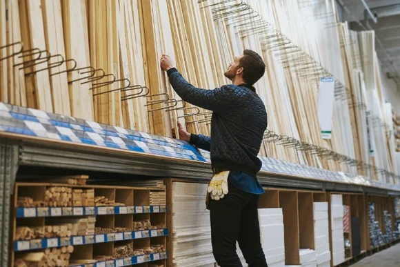 Person sucht in einem Baumarkt nach Holzlatten.