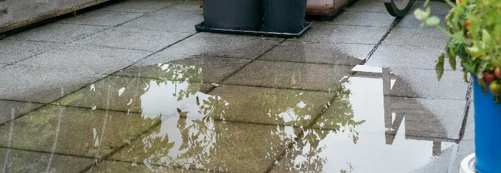 Wasserpfütze auf Fliesen im Garten