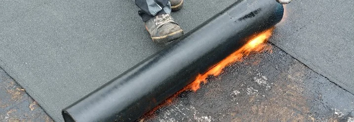 Person verklebt Dachbahnen mit Gasbrenner