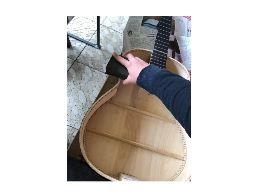 Person schleift Gitarrenkorpus