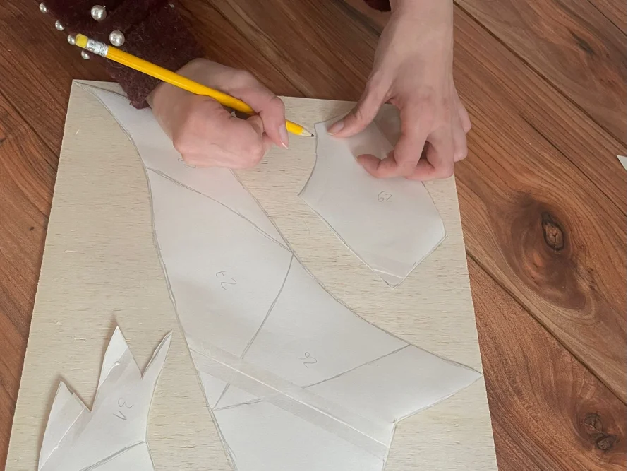 Hände zeichnen mit Bleistift Schnittmuster auf Holzbrett