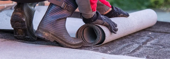 Person rollt Dachpappe aus