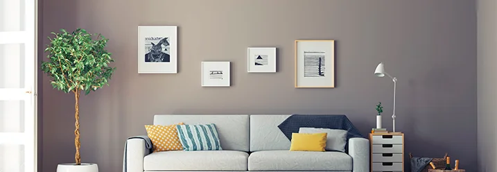 Ein Wohnzimmer mit einer Couch, Bildern an der Wand und einer Pflanze.