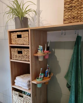 Ein Holzregal in einem Badezimmer mit Körben, Handtüchern und Zahnbürstenhaltern.
