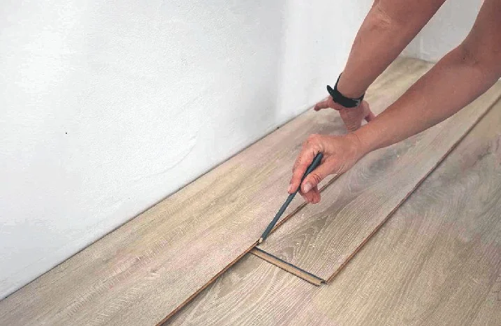 Person zeichnet mit Bleistift auf Laminat