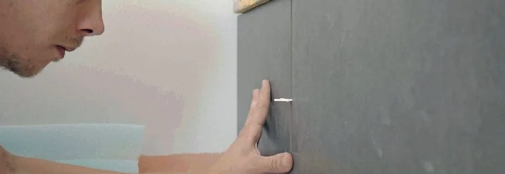 Person bringt Fliese an Wand an