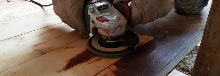 Person schleift Holzdielen mit Schleifmaschine