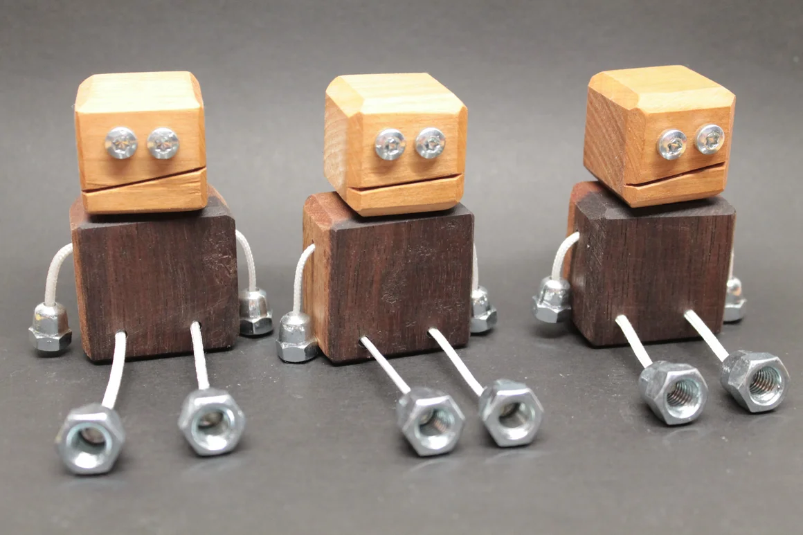 Drei sitzende Roboterfiguren aus Holz, Schrauben und Muttern.