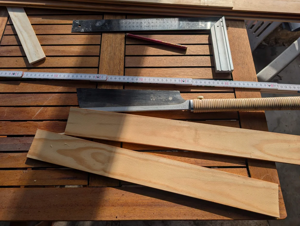 Holzbearbeitungswerkzeuge wie eine Säge und ein Zollstock liegen auf einem Holztisch.