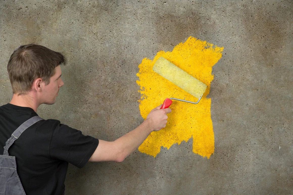 Person streicht Wand gelb