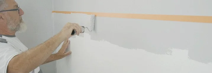Person streicht Wand mit Farbrolle