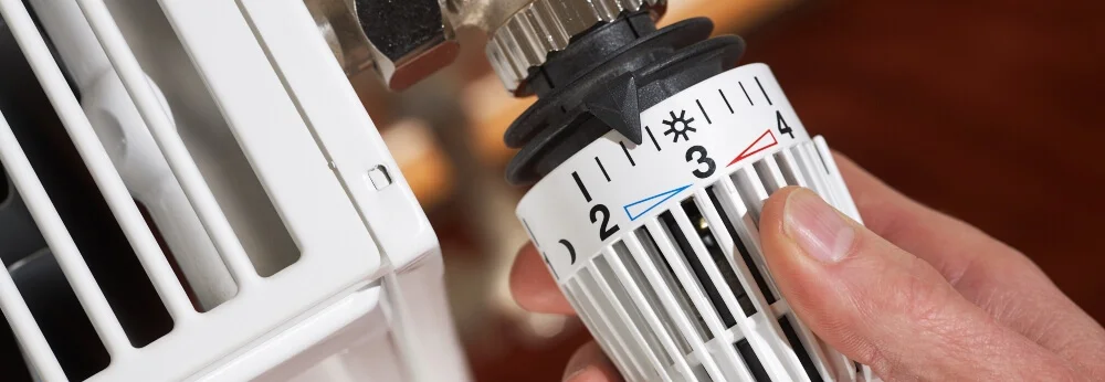 Hand stellt Heizkörperthermostat ein