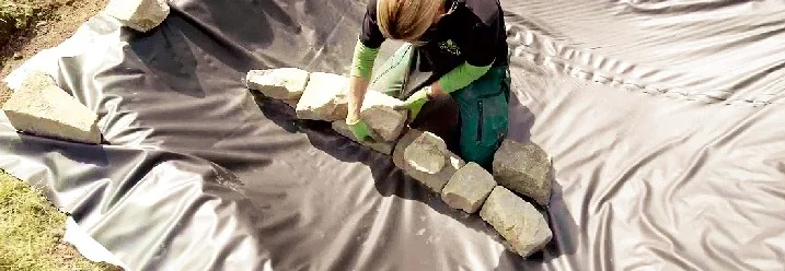 Person baut Steine auf Teichfolie