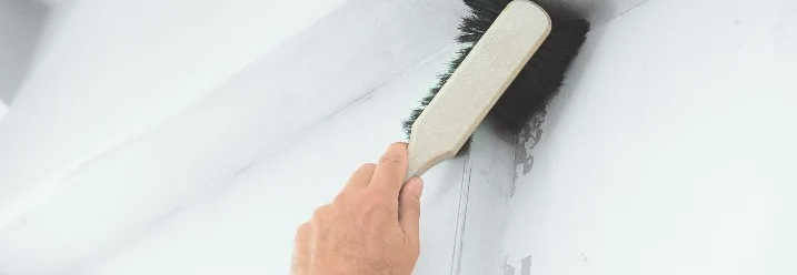 Hand reinigt Wand mit Bürste