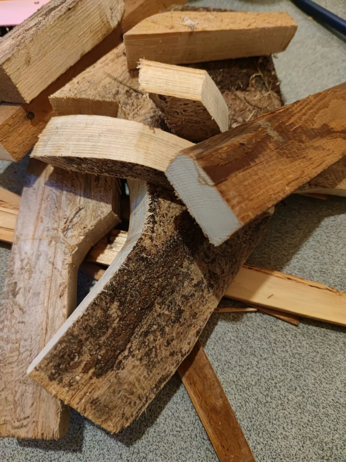 Ein Haufen aus verschiedenen Holzstücken liegt auf dem Boden.