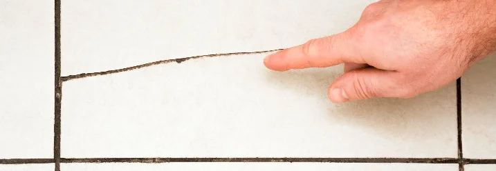 Hand zeigt auf Riss in Fliesen
