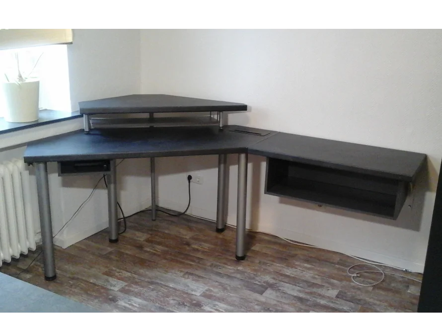 Ein grauer Eck-Computertisch aus Holz.