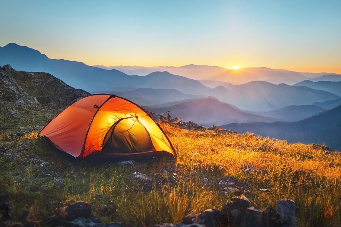 Beleuchtetes Zelt in den Bergen bei Sonnenuntergang