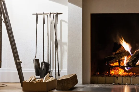 Kamin mit Brennholz und Kaminbesteck