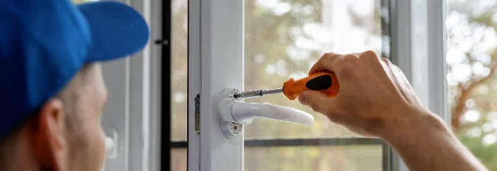 Person montiert Fenstergriff mit Schraubendreher.