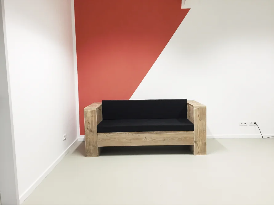 Holzcouch an Wand mit geometrischem Muster