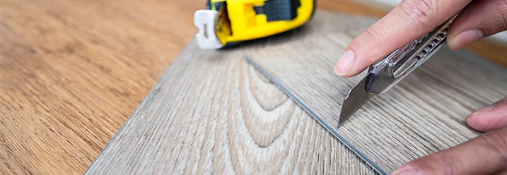 Person schneidet Vinylboden mit Cuttermesser