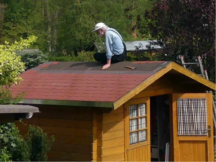 Person deckt ein Gartenhaus.