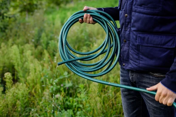 Person hält tropfenden Gartenschlauch