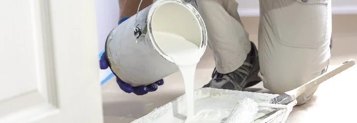 Person gießt Farbe in Farbwanne