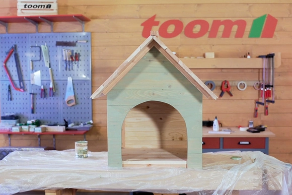 Eine Holz-Hundehütte steht in einer Werkstatt