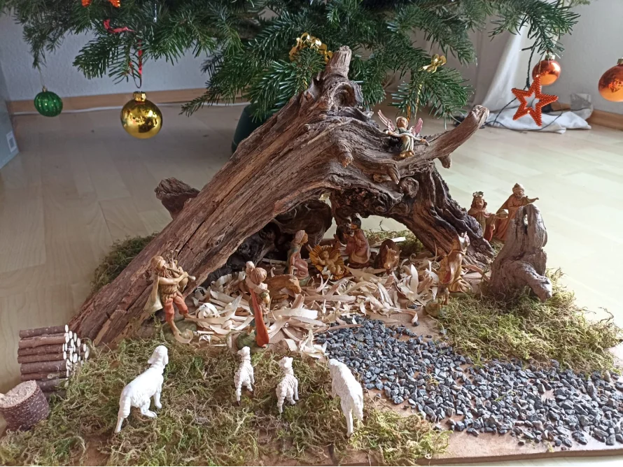 Weihnachtskrippe unter einem Stück Baumstamm