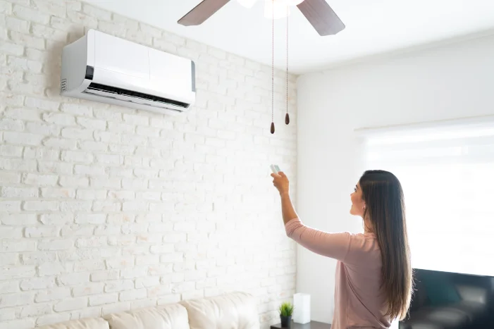 Person bedient Klimaanlage mit Fernbedienung