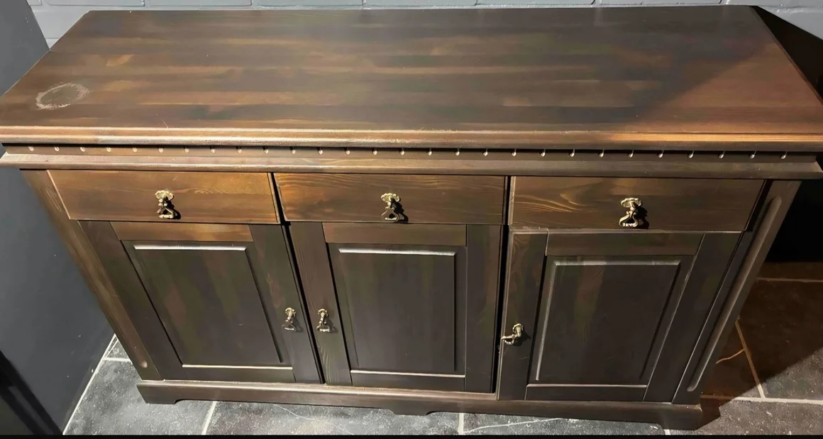 Dunkelbraune Holzkommode mit drei Schubladen und Türen.
