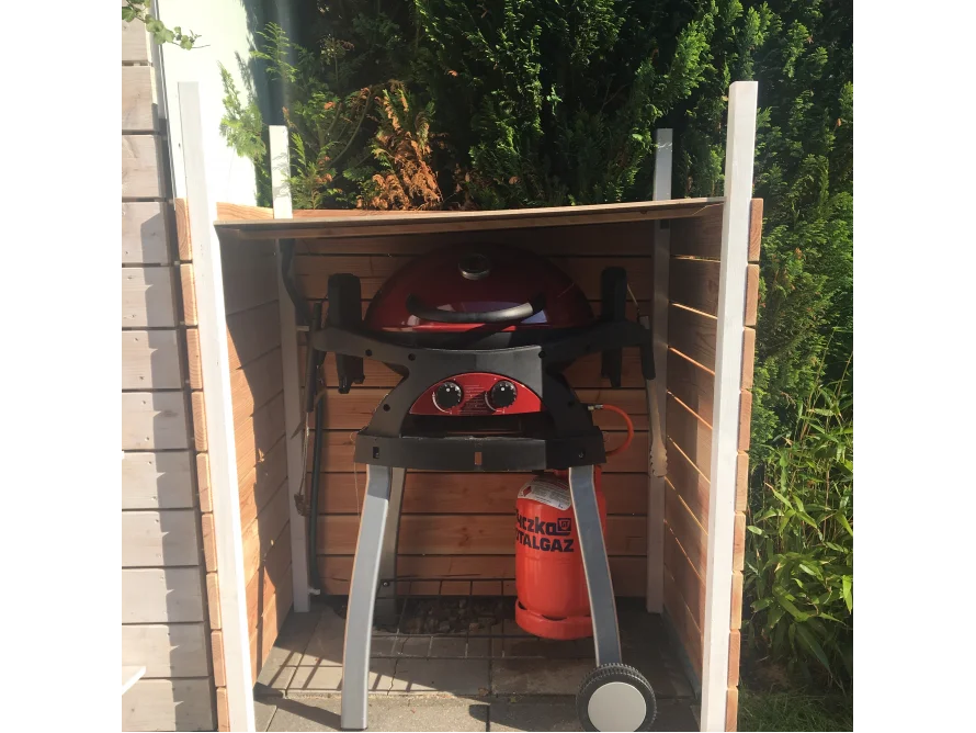 Ein roter Kugelgrill in einem kleinen Schuppen