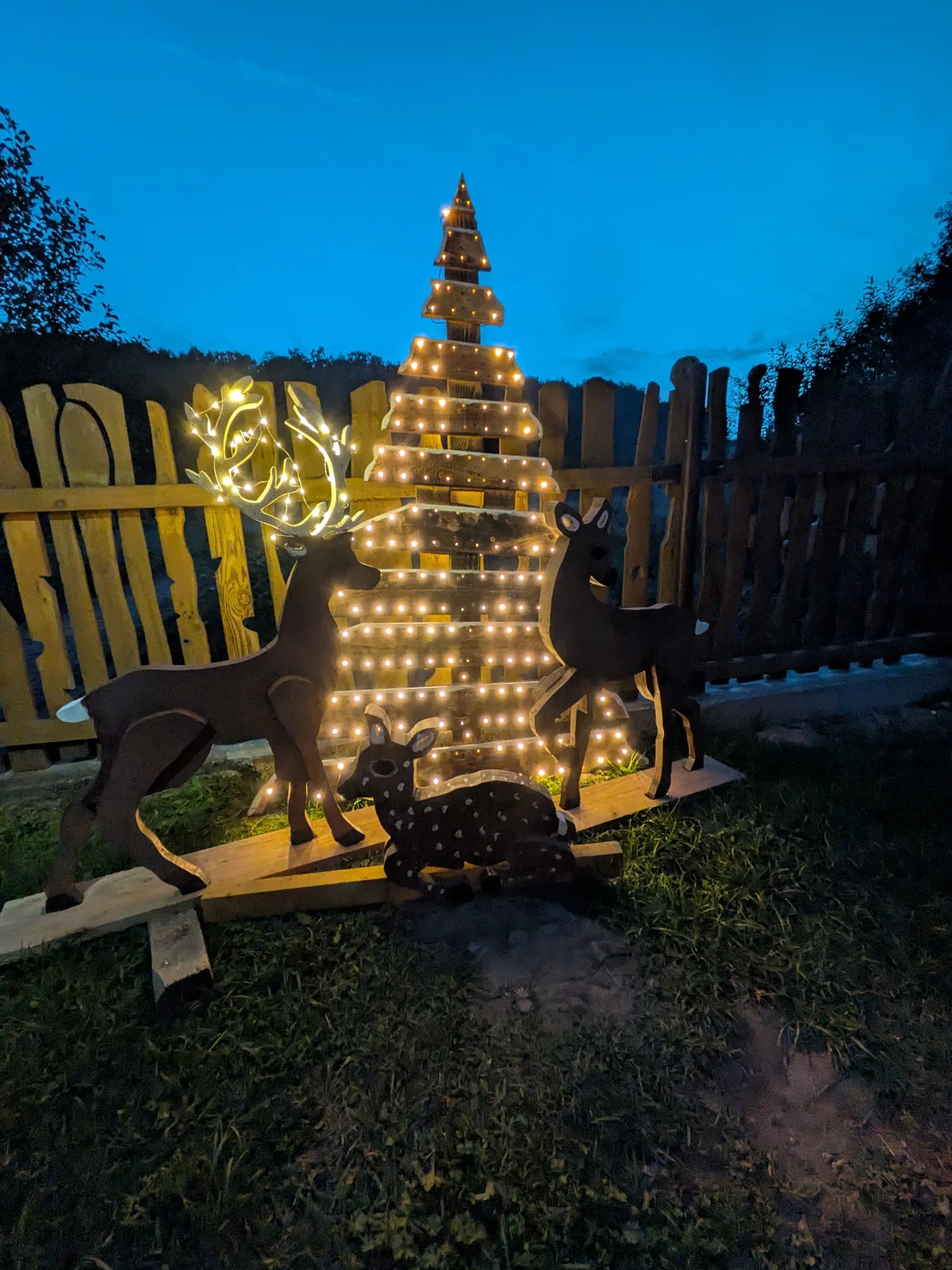 Leuchtende Weihnachtsdekoration aus Holz mit Rehen und Tannenbaum.