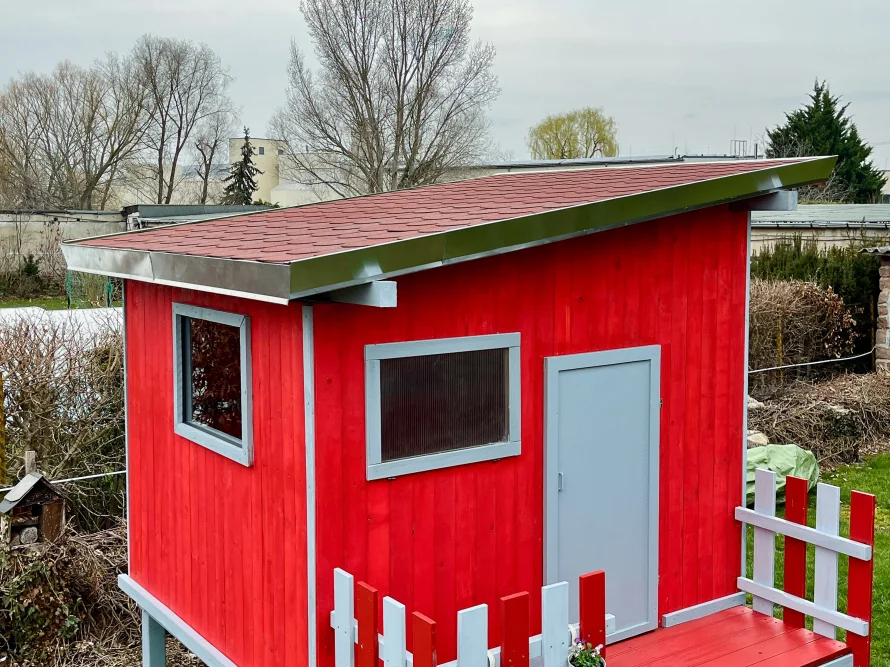 Rotes Gartenhaus mit grau abgesetzten Fenstern und Tür