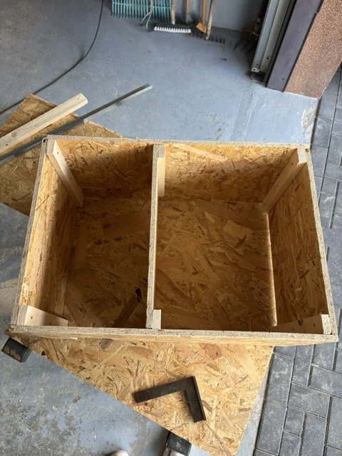 Eine Holzkiste aus OSB-Platten im Bau mit einem Anschlagwinkel.