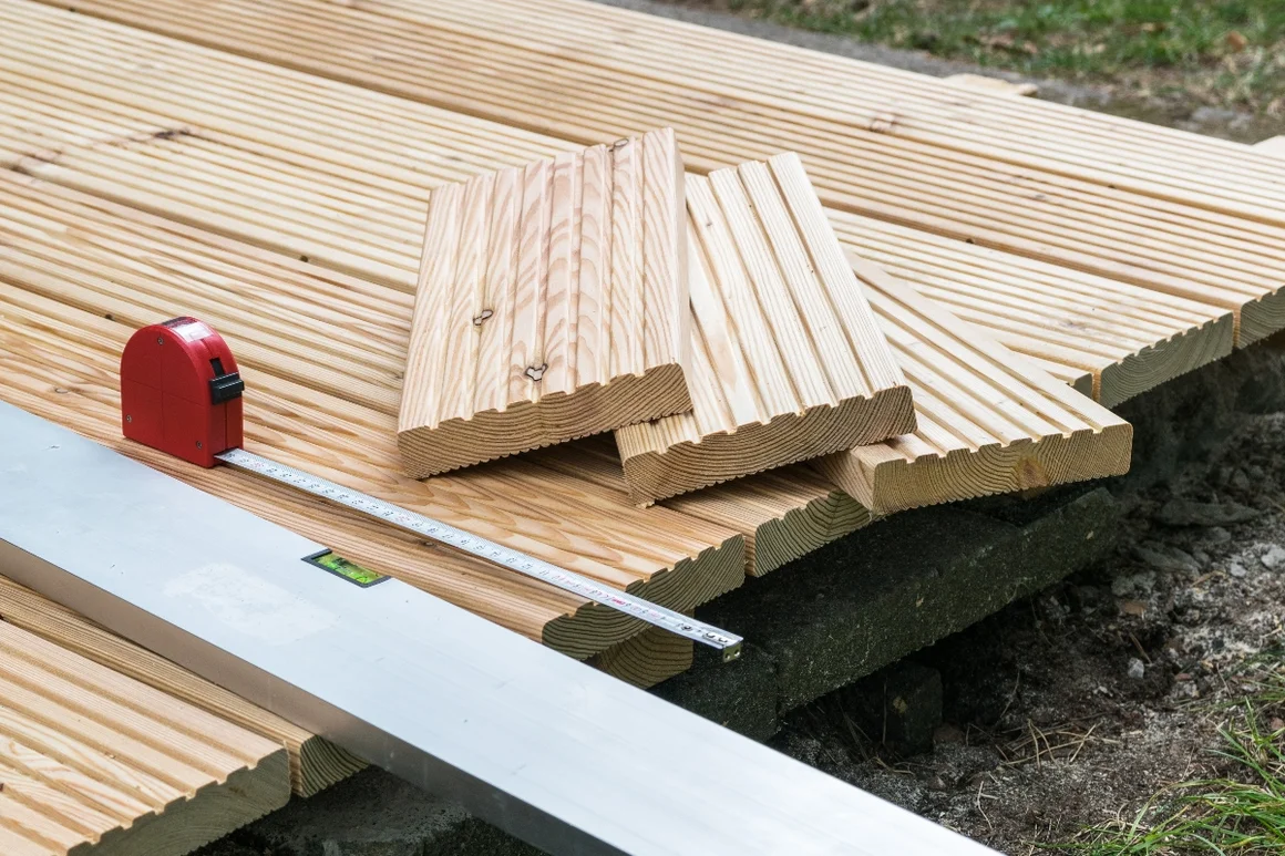 Holzlatten, Zollstock und Wasserwaage auf einem Holzdeck