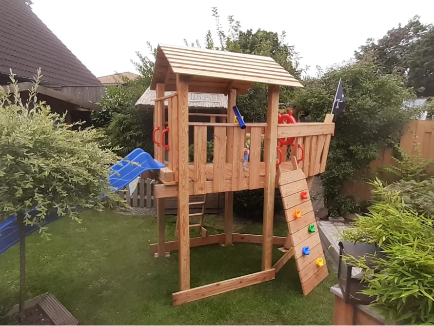 Hölzernes Spielgerät im Garten mit Rutsche und Kletterwand