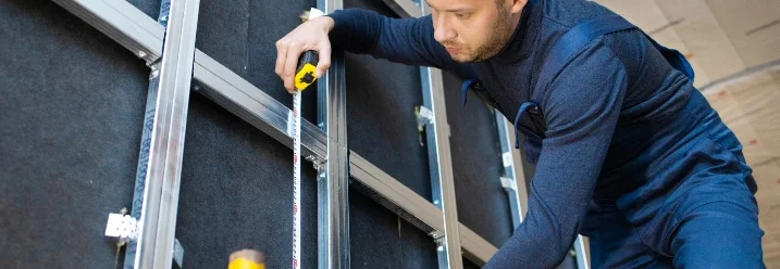 Person misst Wand mit Zollstock aus